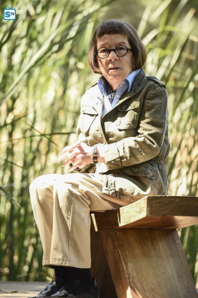 Hetty Lange (Linda Hunt) assise sur un banc dans un jardin boodiste