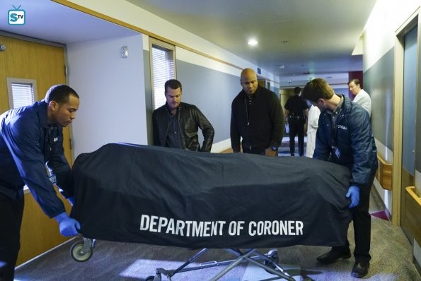 Deux agents de la morgue évacuent un corps dans un sac mortuaire sous les yeux de Sam et Callen
