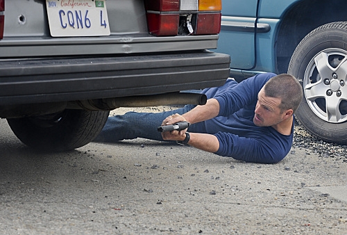 Callen (Chris O'Donnell) se protège derrière une voiture pour tirer sur un suspect